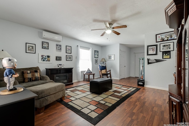 living room with ceiling fan, dark hardwood / wood-style floors, a wall unit AC, and a textured ceiling