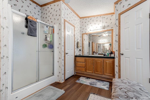 bathroom with crown molding, hardwood / wood-style flooring, vanity, a textured ceiling, and a shower with shower door