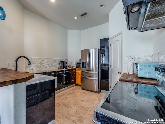 kitchen featuring stainless steel refrigerator with ice dispenser, sink, stove, light tile patterned floors, and backsplash