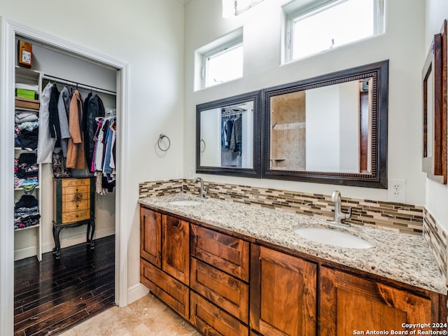 bathroom with hardwood / wood-style floors, dual vanity, and tasteful backsplash