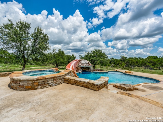 view of pool with an in ground hot tub and a water slide