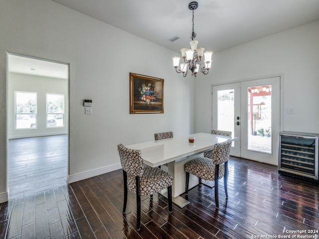 dining space with dark hardwood / wood-style flooring, a healthy amount of sunlight, a chandelier, and beverage cooler