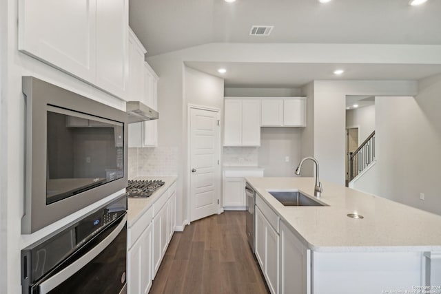 kitchen with sink, backsplash, appliances with stainless steel finishes, a kitchen island with sink, and white cabinets