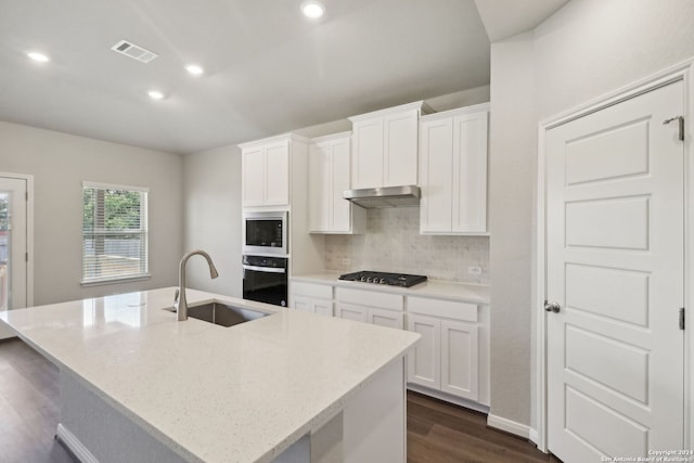 kitchen with black oven, white cabinetry, an island with sink, sink, and light stone countertops