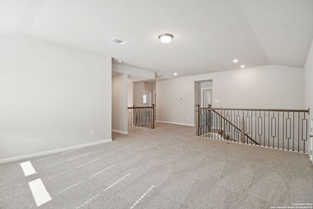 carpeted empty room with vaulted ceiling