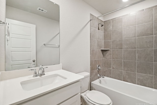 full bathroom featuring tiled shower / bath, vanity, and toilet