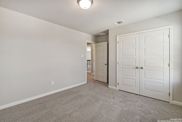 unfurnished bedroom featuring light colored carpet and a closet