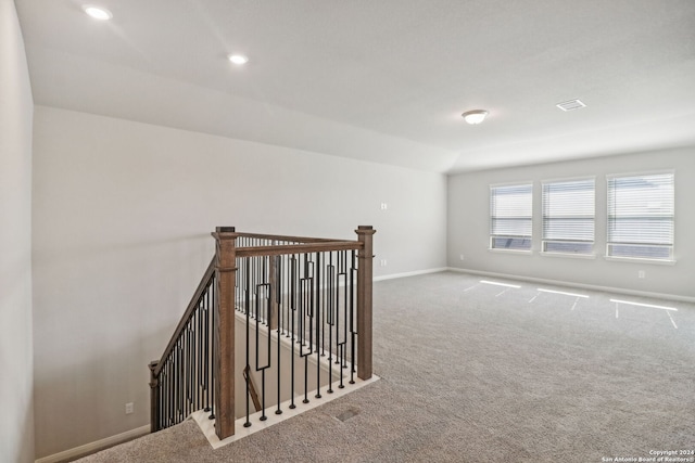 carpeted empty room featuring vaulted ceiling