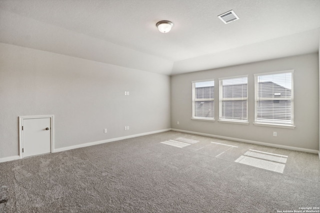 carpeted spare room with vaulted ceiling