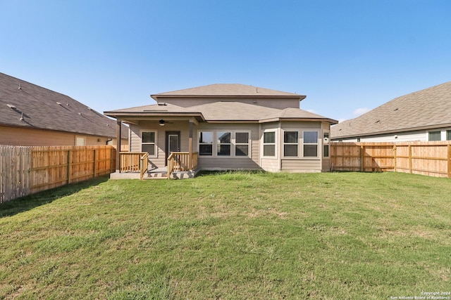 back of property with ceiling fan and a lawn