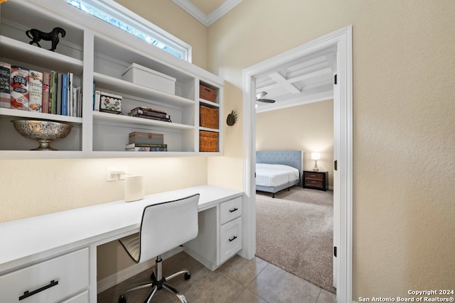 office space with crown molding, ceiling fan, built in desk, coffered ceiling, and light carpet