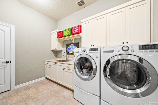 laundry room featuring sink, cabinets, light tile patterned floors, a textured ceiling, and washer and dryer