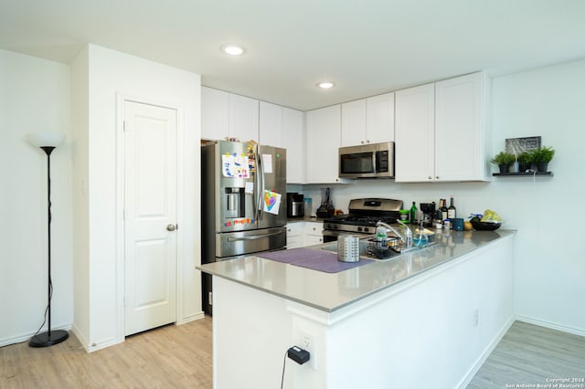 kitchen featuring appliances with stainless steel finishes, white cabinetry, kitchen peninsula, and light wood-type flooring