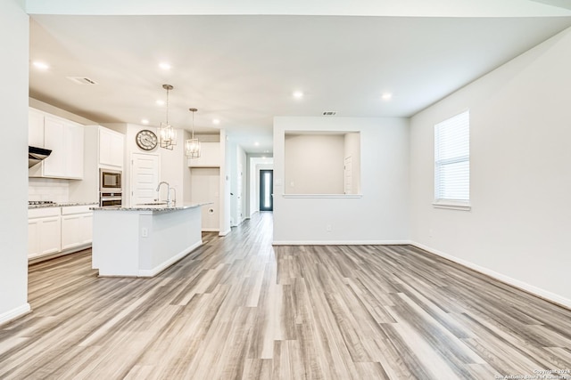 kitchen featuring sink, white cabinetry, a center island with sink, light wood-type flooring, and appliances with stainless steel finishes