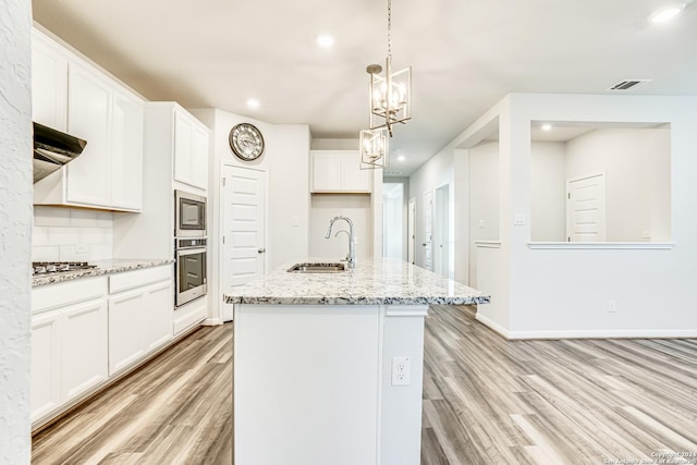 kitchen featuring appliances with stainless steel finishes, white cabinetry, sink, a kitchen island with sink, and light wood-type flooring