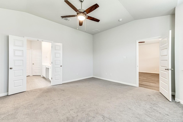 unfurnished bedroom featuring ensuite bath, vaulted ceiling, light colored carpet, and ceiling fan