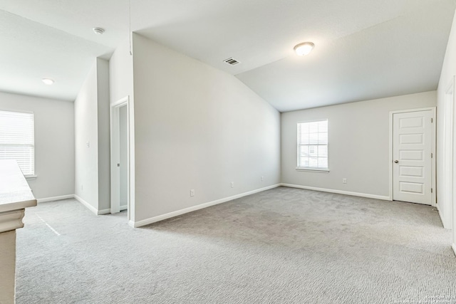 carpeted spare room with lofted ceiling