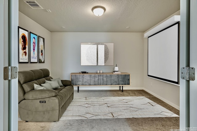 carpeted home theater room featuring a textured ceiling