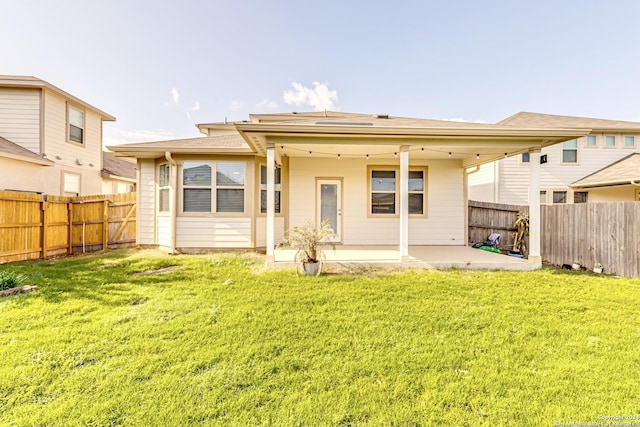 back of property with a lawn and a patio