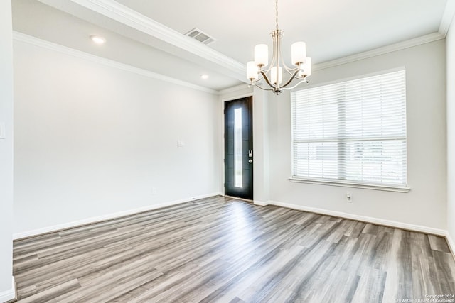 empty room featuring an inviting chandelier, crown molding, and light wood-type flooring