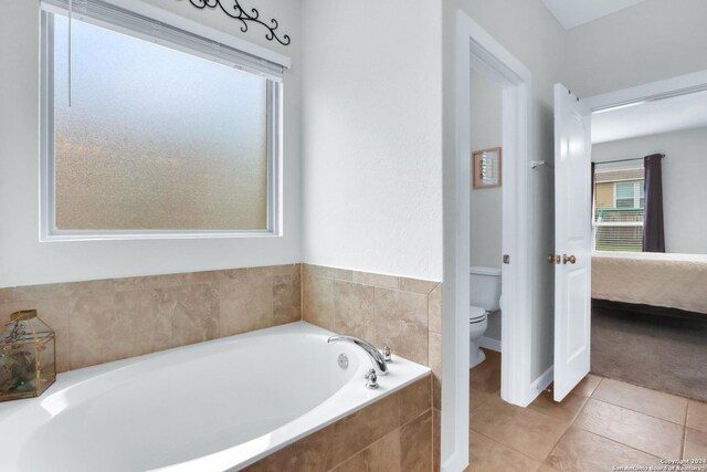 bathroom with tile patterned floors, tiled bath, and toilet