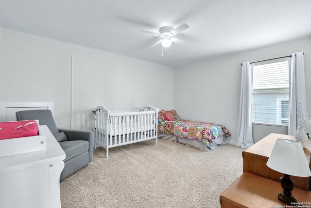 bedroom featuring ceiling fan, carpet floors, and a nursery area