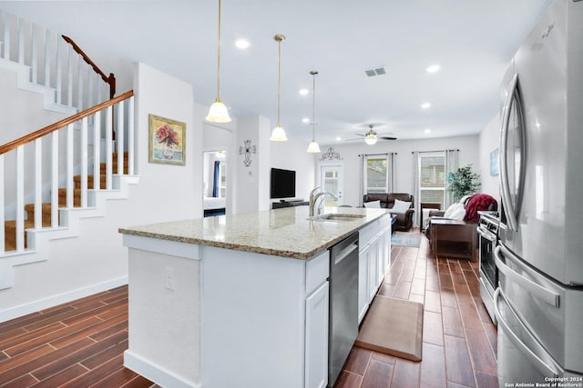 kitchen featuring a center island with sink, dark hardwood / wood-style flooring, white cabinetry, light stone countertops, and stainless steel appliances