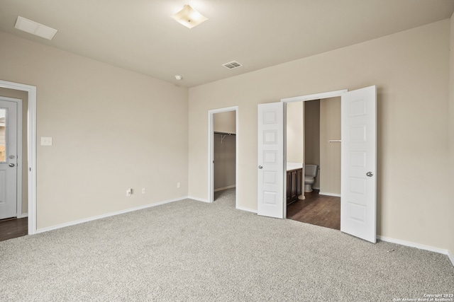 unfurnished bedroom with ensuite bathroom, carpet flooring, and a spacious closet