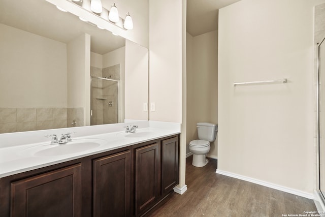 bathroom with toilet, an enclosed shower, hardwood / wood-style floors, and double vanity