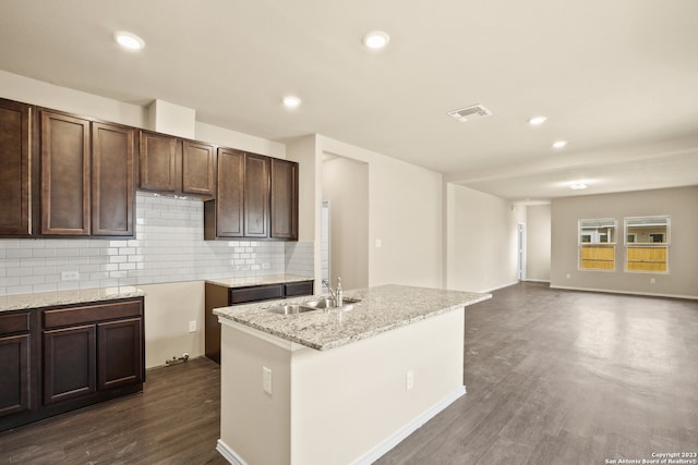 kitchen featuring sink, dark hardwood / wood-style flooring, a center island with sink, and backsplash