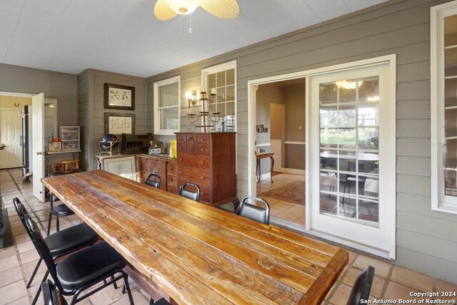 dining space featuring ceiling fan and wooden walls