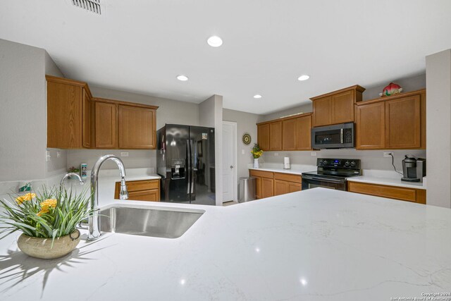 kitchen with black appliances, light tile patterned floors, sink, a breakfast bar area, and kitchen peninsula