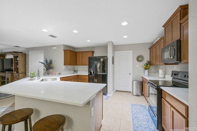 kitchen featuring black appliances, sink, a kitchen breakfast bar, light tile patterned floors, and kitchen peninsula