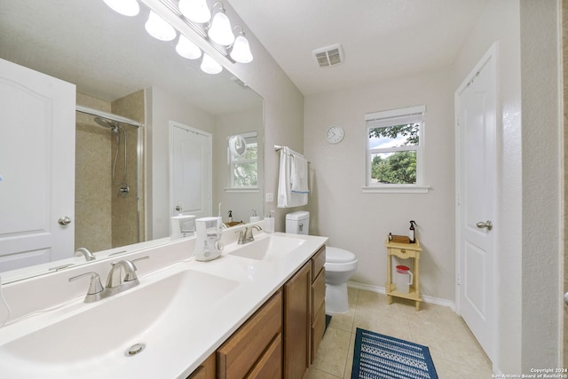 bathroom featuring tile patterned floors, double vanity, a shower with shower door, and toilet