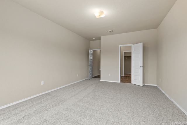 unfurnished bedroom featuring carpet flooring, a closet, and a spacious closet