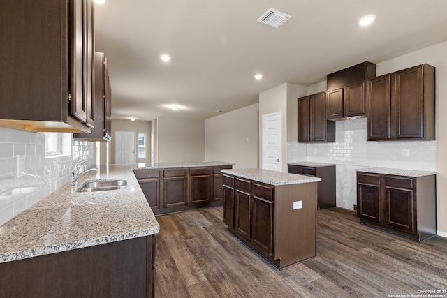 kitchen with tasteful backsplash, sink, a center island, dark brown cabinetry, and dark wood-type flooring