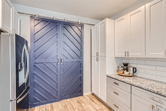 kitchen with backsplash, stainless steel fridge, light wood-style floors, and white cabinetry