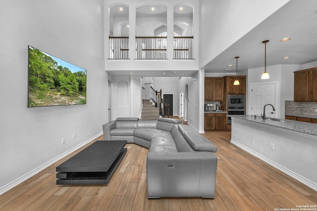 living room with sink, a towering ceiling, and light wood-type flooring