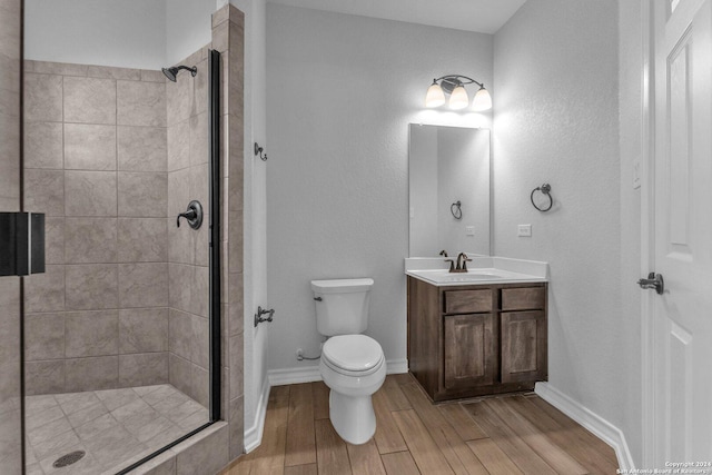 bathroom featuring vanity, wood-type flooring, toilet, and a tile shower