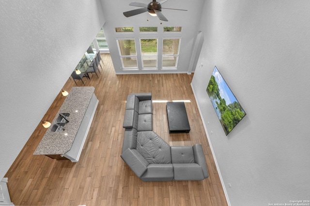 living room featuring ceiling fan, light hardwood / wood-style floors, and a high ceiling