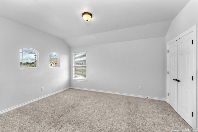 unfurnished room featuring vaulted ceiling and carpet