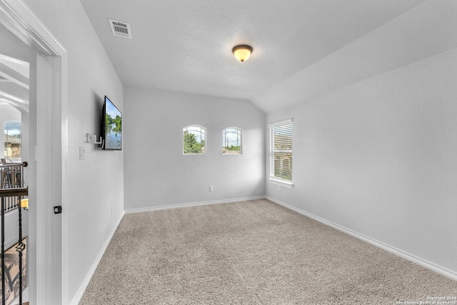 carpeted spare room with lofted ceiling