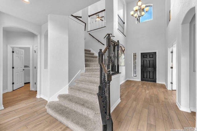 entrance foyer with a towering ceiling, a notable chandelier, and light wood-type flooring