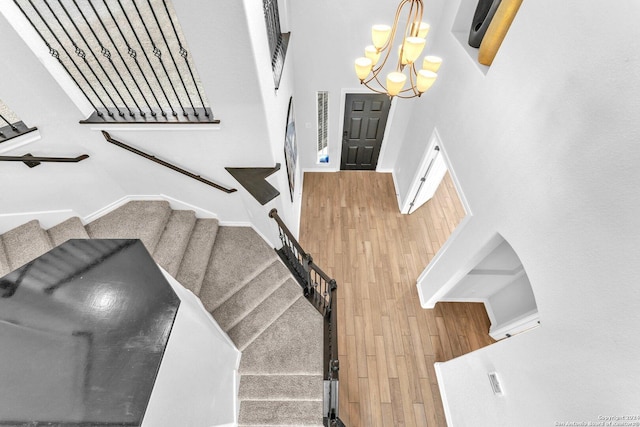 stairway featuring an inviting chandelier, wood walls, and a high ceiling