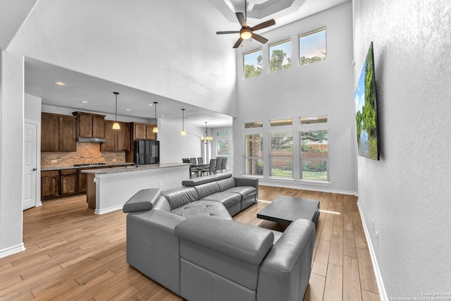 living room featuring plenty of natural light, light wood-type flooring, and a high ceiling