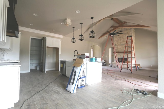 kitchen featuring white cabinets, ventilation hood, decorative light fixtures, vaulted ceiling with beams, and ornamental molding