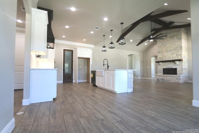 kitchen featuring a kitchen island with sink, white cabinets, custom exhaust hood, decorative backsplash, and decorative light fixtures