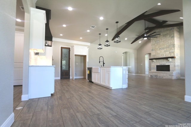 kitchen with pendant lighting, ceiling fan, an island with sink, and white cabinets