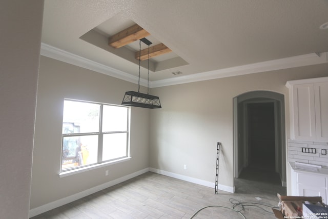 empty room featuring light hardwood / wood-style floors, a tray ceiling, ornamental molding, and beamed ceiling