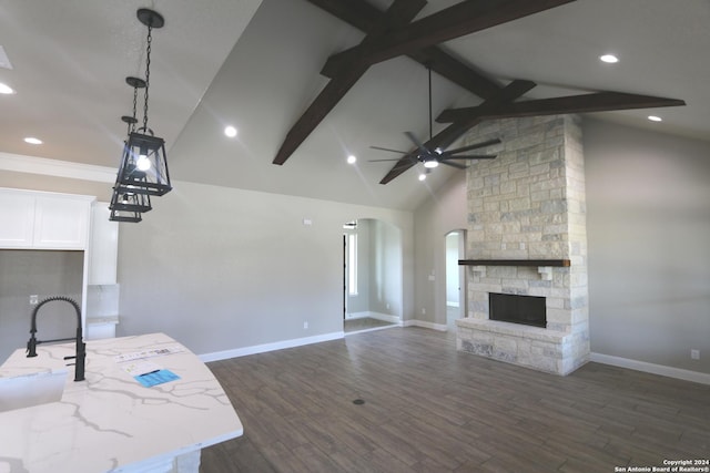 kitchen featuring a fireplace, white cabinets, hanging light fixtures, light stone countertops, and dark wood-type flooring